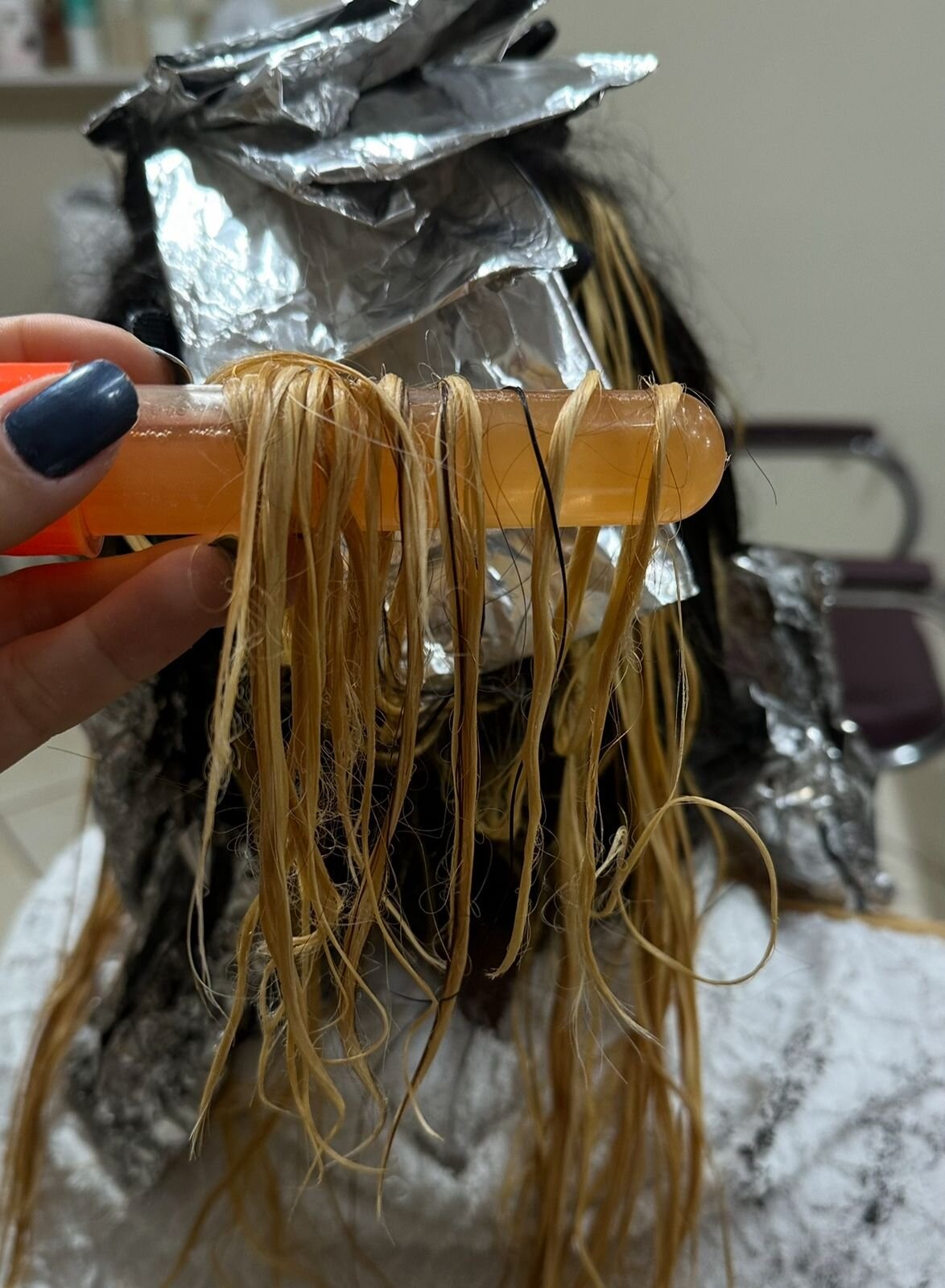 Mecha de cabelo sendo testada em tubo de vidro antes da aplicação de um processo químico, mostrando o teste de mecha em salão