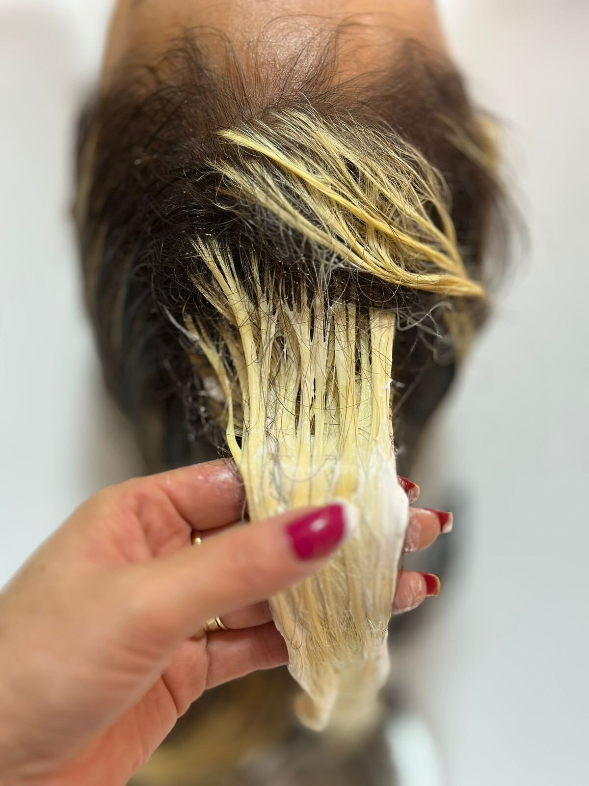 Mechas de cabelo recebendo pasta descolorante na raiz durante avaliação da estrutura do fio